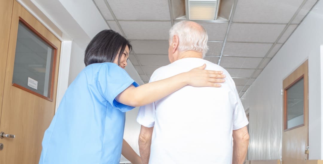 A Brickyard Healthcare nurse helps a patient through the hall.