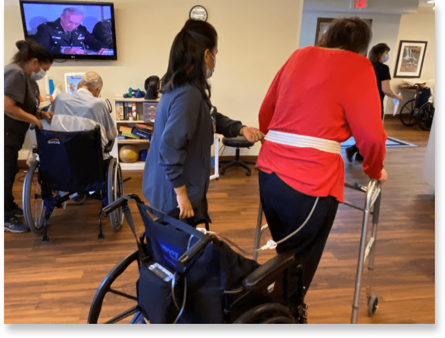 A Brickyard Healthcare caregiver helps a resident transition from wheelchair to walker.