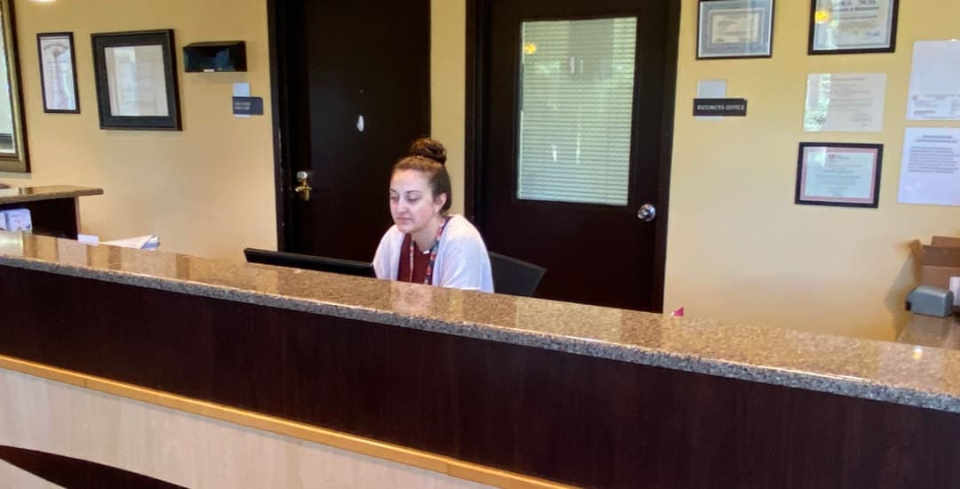 A Brickyard Healthcare team member sits behind the front desk of a care center.