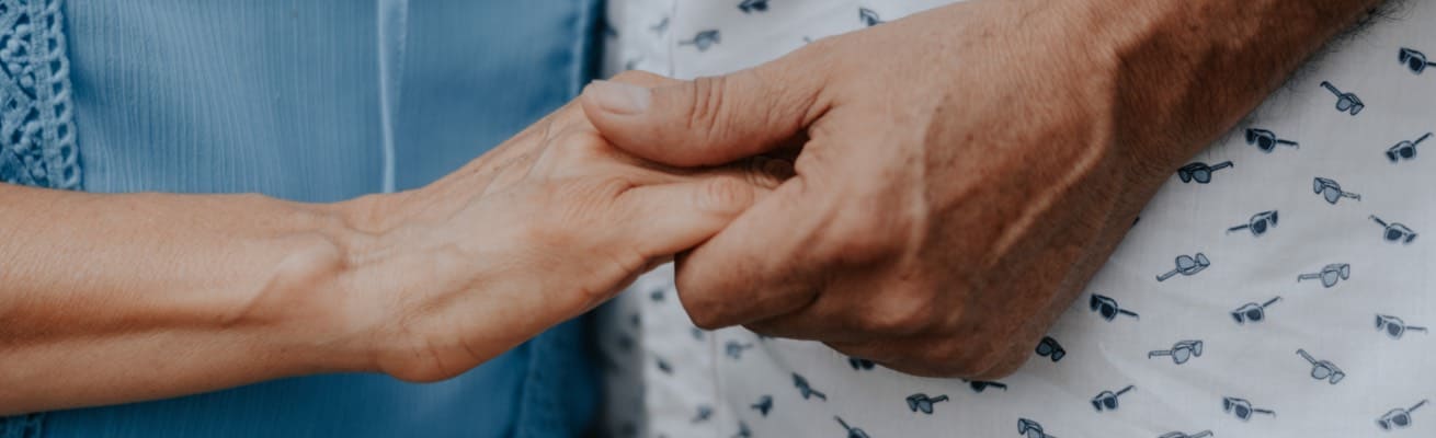 A nurse and patient holding hands.