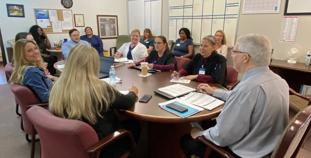 Members of the Brickyard Healthcare team meet at a conference table.